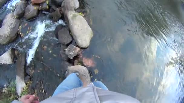 Мужчина помогает женщине перейти реку — стоковое видео