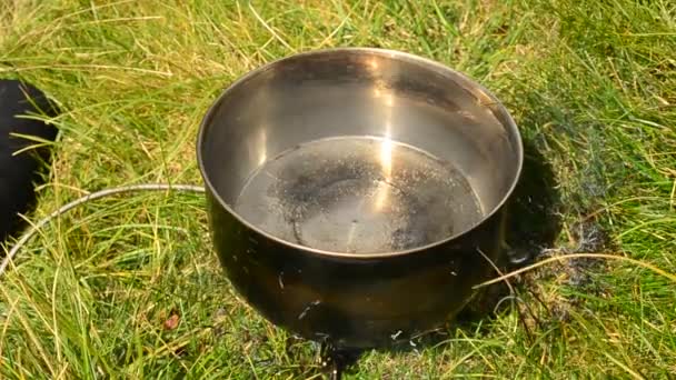 Water boiling in a saucepan on fire outdoors — Stock Video