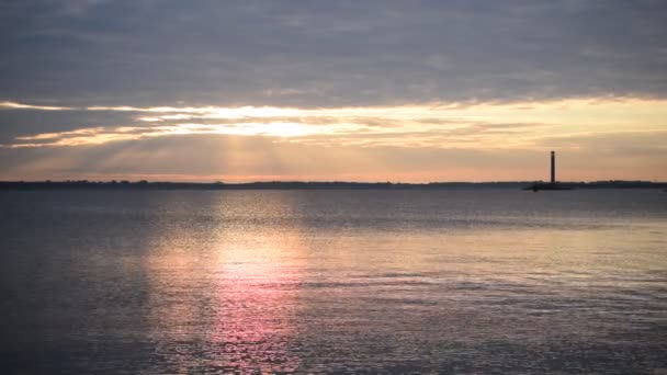 Барвистий схід сонця над водою з маяком далеко — стокове відео