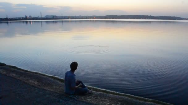 Man skips stones on water in the evening — Stock Video