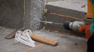 Çalışan eller perforator ile ev temel üzerine bir delik delme