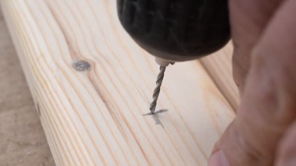 Handen boren een klein gaatje in een grenen houten plank — Stockvideo