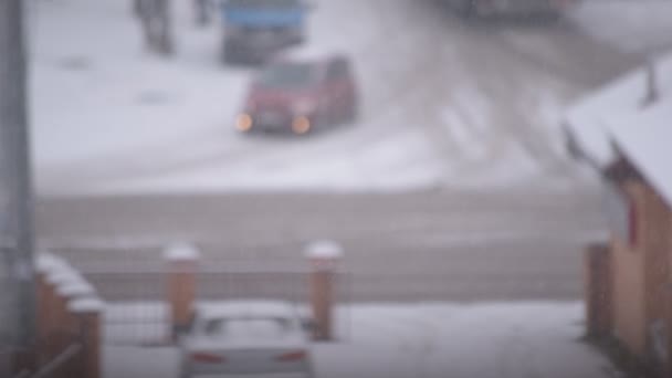 Снег в городе на фоне дороги с автомобилями и людьми — стоковое видео