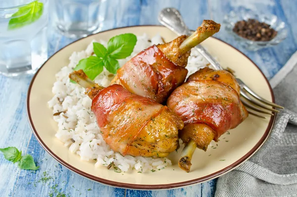 Bacon wrapped chicken legs with rice garnish