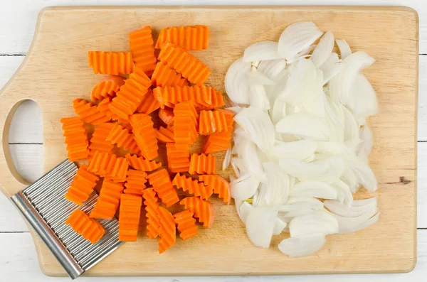 Variously sliced for cooking carrots and onions on a cutting boa — Stock Photo, Image