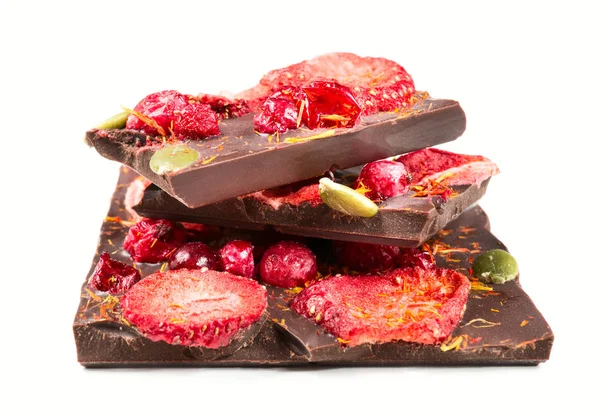 Pila de trozos de chocolate con fresas secas y arándanos sobre fondo blanco . — Foto de Stock