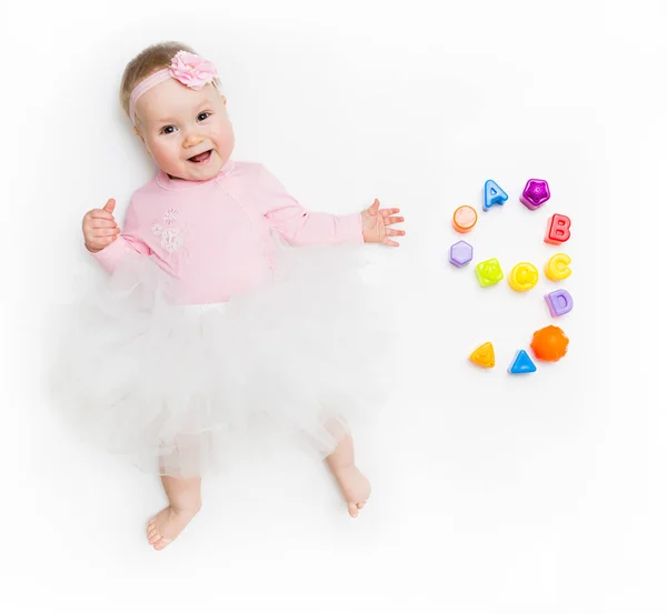 Retrato de una niña dulce con un vestido rosa y un lazo de diadema, aislado en blanco en el estudio con el número nueve de juguetes . —  Fotos de Stock