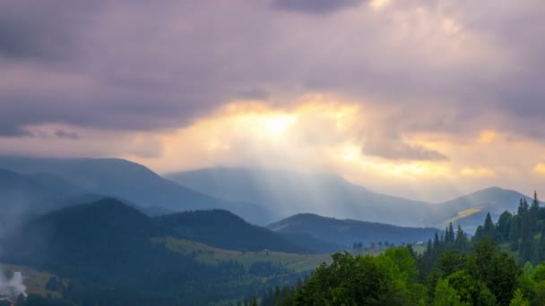 Los rayos del sol pasan a través de las nubes sobre las montañas al atardecer . — Vídeos de Stock