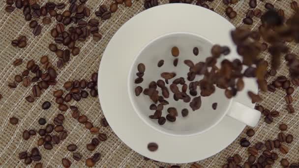 Ganze Kaffeebohnen fallen in die Tasse. — Stockvideo