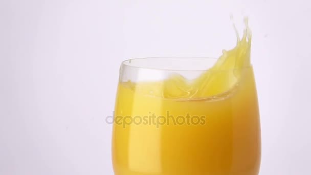 Plasterek pomarańczy, popadania w szklankę soku pomarańczowego. — Wideo stockowe