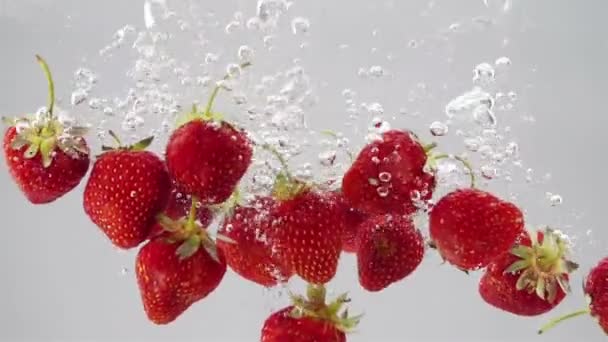 Reife Erdbeeren fallen durch das Wasser. — Stockvideo