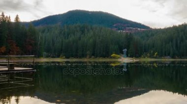 Dağ gölü renkli ağaçlar orman ve su üzerinde düşen yapraklar ile sonbahar günbatımı. Timelapse.