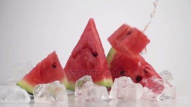 Masada buz küpleri ve karpuz dilimleri düşen karpuz küpleri. Çok yavaş hareket.