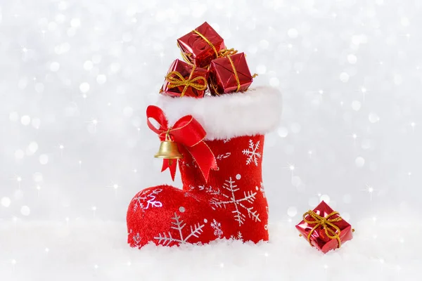 Červené vánoční Punčocha s dary, santas bota do sněhu, bokeh a snowflackes — Stock fotografie