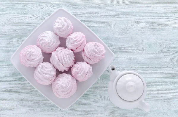 Mooie pastel roze schuimgebak, zephyrs, marshmallows en een theepot op de houten vintage tafel — Stockfoto