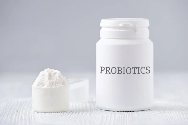 Glas und Löffel mit probiotischem Pulver auf grau — Stockfoto