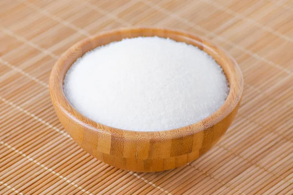 Uma tigela de madeira com açúcar branco na textura de bambu — Fotografia de Stock