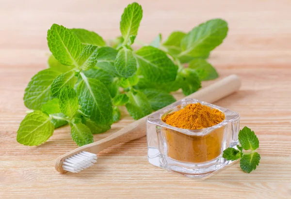 Alternatif doğal diş macunu zerdeçal tozu, curcuma ve ahşap diş fırçası, üzerinde ahşap nane