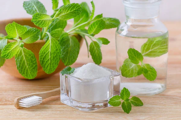 Alternativa naturliga munvatten flaska med tandkräm xylitol, soda, salt och trä tandborste närbild, mint på trä — Stockfoto