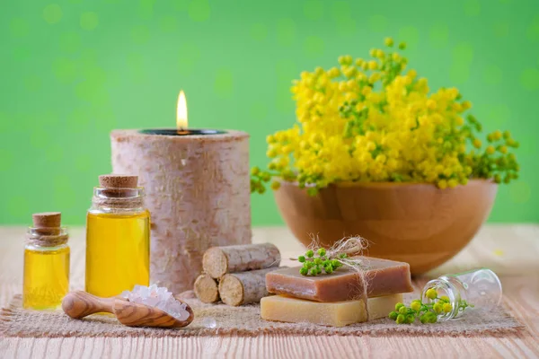 Sağlık, spa ve aromaterapi temel yağlar, sabun, taze bitki, mum ile tuz yeşil arka planda, seçici odak