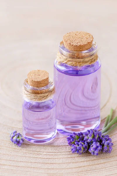 Levandulový olej v lahvích a čerstvé levandulové květy na pařez a dřevěné pozadí — Stock fotografie