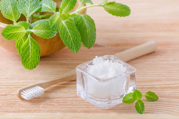 Alternative natural toothpaste coconut oil and wood toothbrush closeup, mint on wooden — Stock Photo, Image