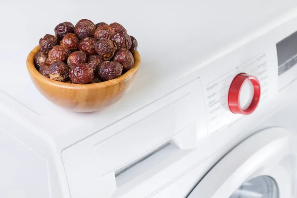 Мыльные орешки в миске на стиральной машине, органическое моющее средство, избирательный фокус — стоковое фото