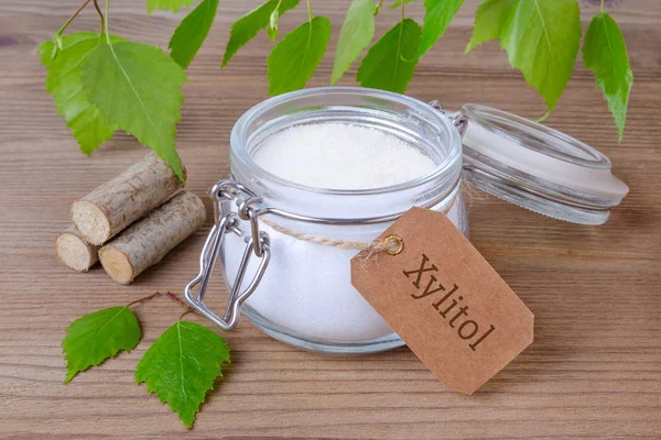 Substitut de sucre xylitol, un bocal en verre avec du sucre de bouleau, des liefs et du bois — Photo