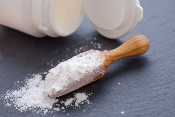 Wooden scoop with probiotic powder on black — Stock Photo, Image