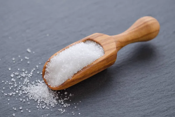 Xylitol or birch sugar in a wooden scoop on black background, selective focus — Stock Photo, Image
