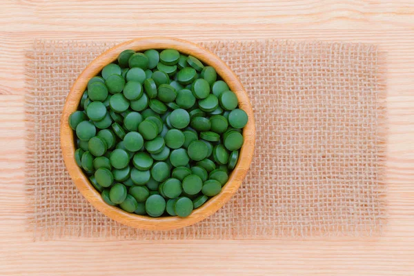 Grüne Pillen Spirulina und Chlorella Algen aus nächster Nähe in einer hölzernen Schüssel Draufsicht mit Rahmen — Stockfoto