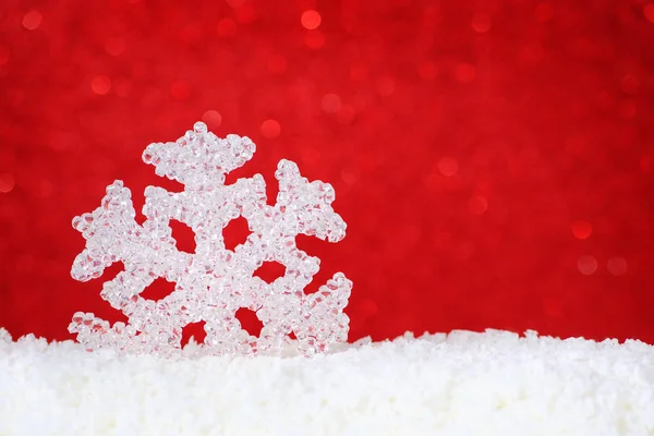 Snowflake in snow on red background with copy space — Stock Photo, Image