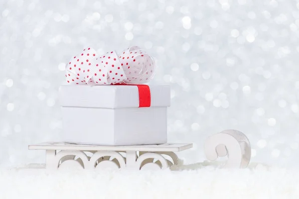 Sleigh in snow with a present and ribbon on christmas background, selective focus — Stock Photo, Image