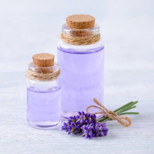 Skleněné lahve aromaterapie olej a čerstvé levandulové květy na dřevěný stůl — Stock fotografie