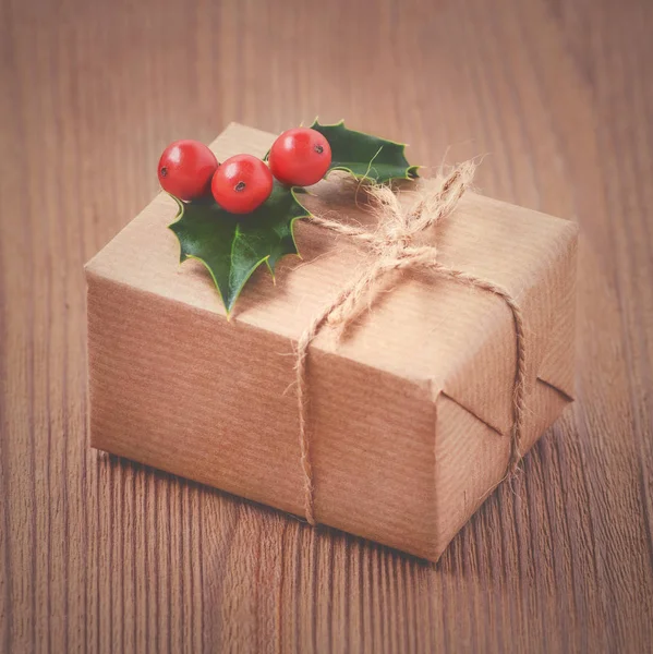 Vintage gift box, kraft paper, rope and holly berries on old wooden — Stock Photo, Image