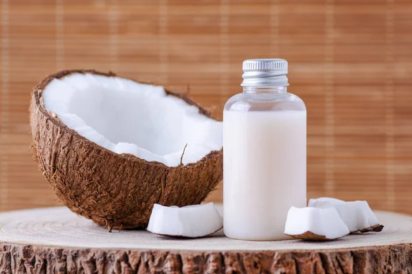 Garrafa cosmética e coco orgânico fresco para cuidados com a pele, fundo natural — Fotografia de Stock