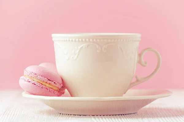 Rózsaszín macaron házi és egy csésze kávét a rózsaszín háttér tónusú — Stock Fotó