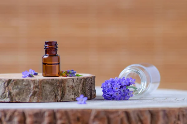Botella de vidrio marrón con aceite esencial de lavanda y flores frescas en madera —  Fotos de Stock