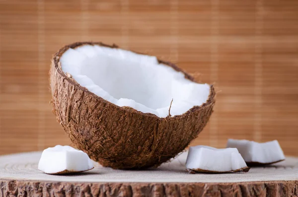 Eine Hälfte Kokosnuss und Stücke auf natürlichem braunem Hintergrund — Stockfoto