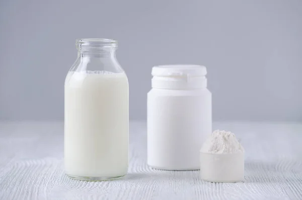 Botella de vidrio de leche y polvo sobre fondo gris —  Fotos de Stock