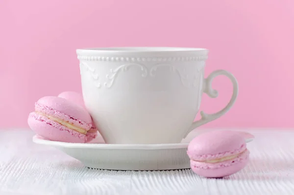 Kaffeetasse mit rosa Makronen auf rosa Hintergrund — Stockfoto