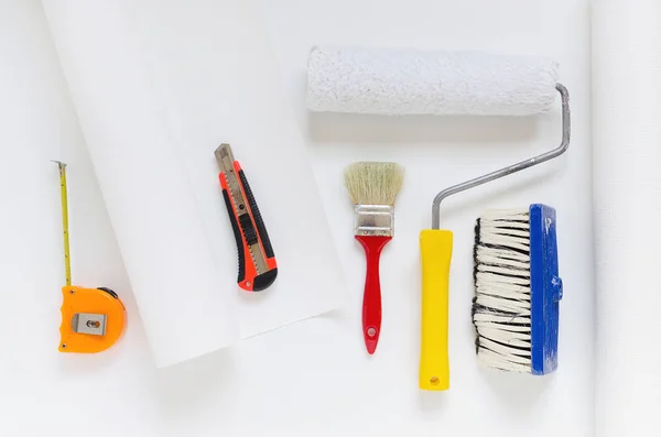 房屋修理设备, 白色墙纸轧辊用油漆辊, 刷子, 卷尺, 刀 — 图库照片