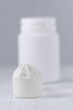 bir kaşık beyaz toz ve bir şişe gri, seçici odak ile