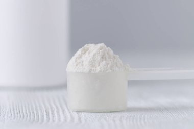 bir kaşık beyaz toz closeup ve gri arka plan üzerinde bir kavanoz
