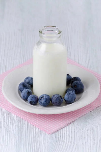 Szklana butelka z piciem jogurtu z blueberrys na stole — Zdjęcie stockowe