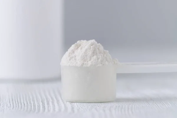 bir kaşık beyaz toz closeup ve gri arka plan üzerinde bir kavanoz
