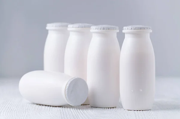 Beber iogurte em garrafas de plástico em fundo cinza — Fotografia de Stock