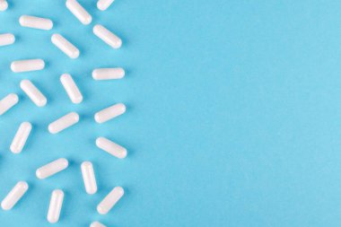 Mavi arkaplanda kopyalama alanı olan beyaz ilaç kapsülleri