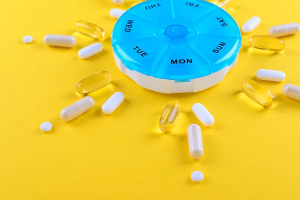 Verschillende geneesmiddelen voor een week en een pillendoos op gele achtergrond — Stockfoto
