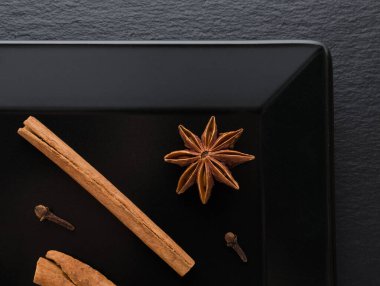 Tarçın çubukları, karanfil ve anason siyah tabakta